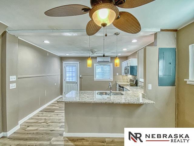 kitchen featuring sink, white cabinetry, electric panel, hanging light fixtures, and light stone countertops