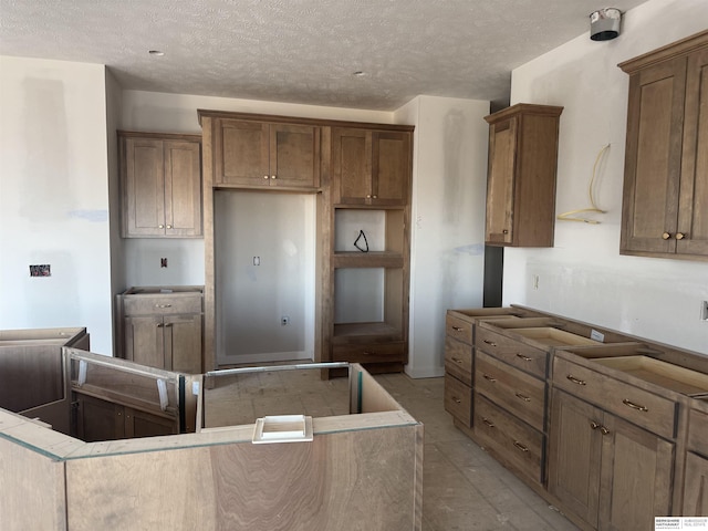 kitchen with a center island, a textured ceiling, and brown cabinetry