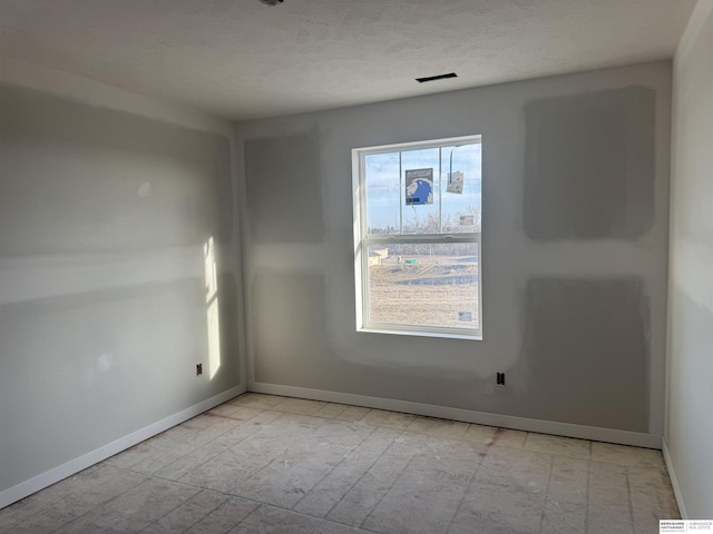 unfurnished room with baseboards, visible vents, and a textured ceiling