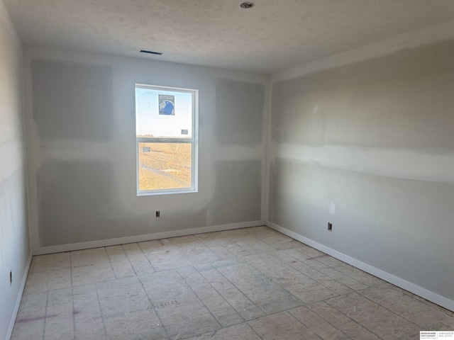 unfurnished room with visible vents, baseboards, and a textured ceiling