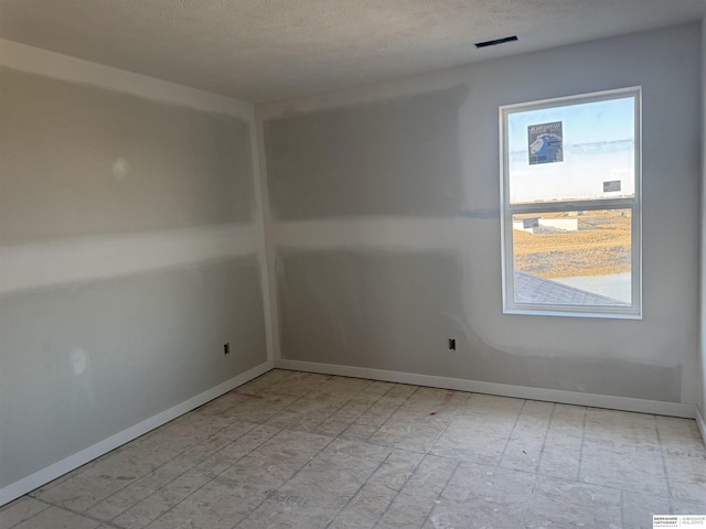 unfurnished room featuring a textured ceiling and baseboards