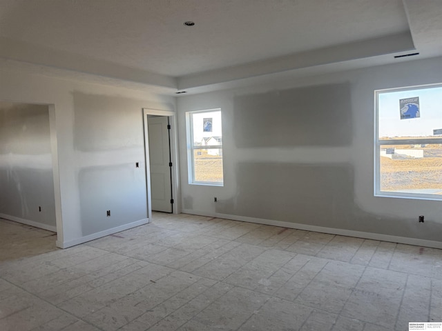 spare room with a tray ceiling and baseboards