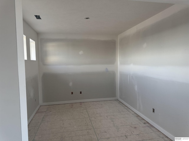 unfurnished room with baseboards