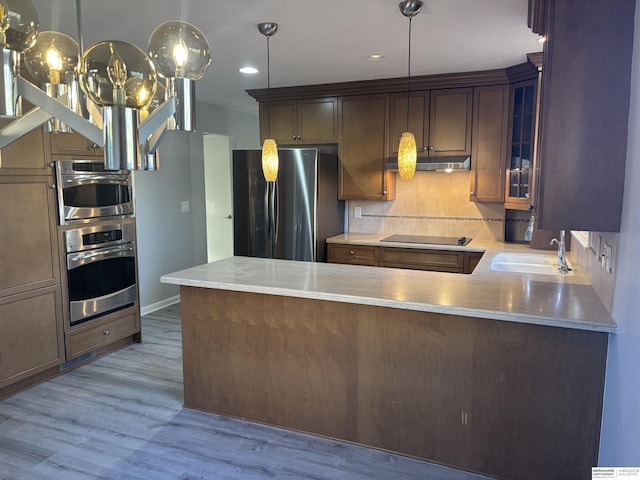 kitchen with kitchen peninsula, stainless steel fridge, light hardwood / wood-style floors, black electric stovetop, and sink