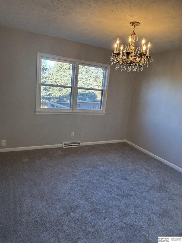 carpeted empty room with a textured ceiling and an inviting chandelier