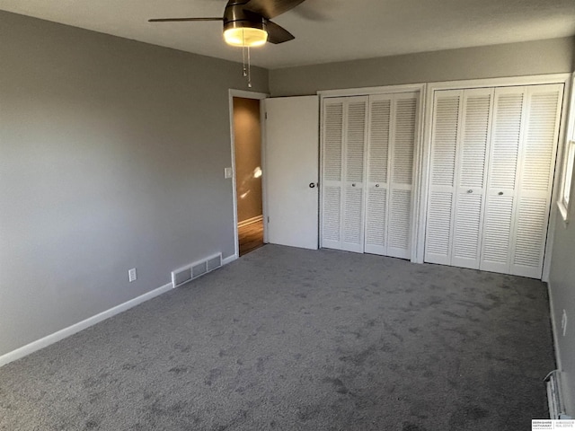 unfurnished bedroom featuring two closets, ceiling fan, and carpet