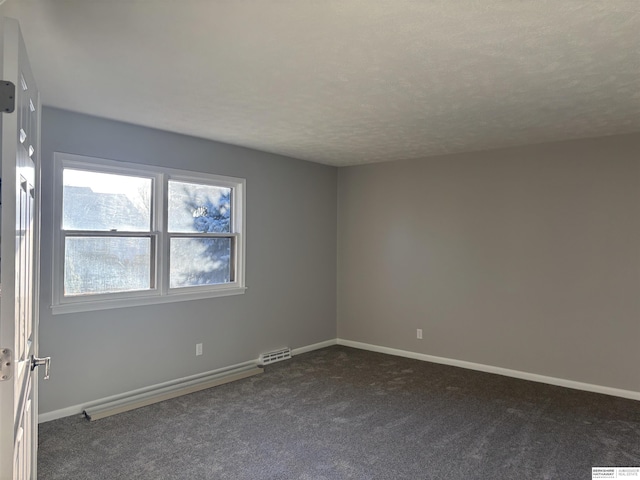 empty room with dark carpet and a textured ceiling