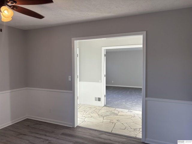 empty room featuring ceiling fan, dark wood-type flooring, and a textured ceiling