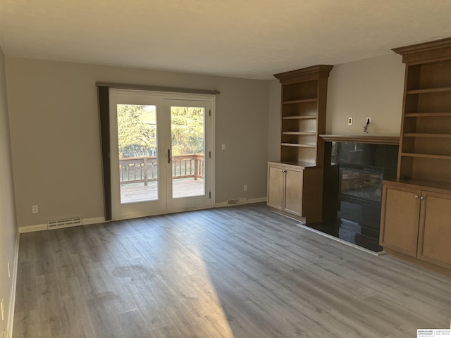 unfurnished living room with light wood-type flooring and a tile fireplace