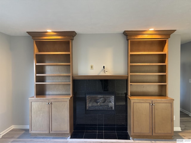 unfurnished living room with hardwood / wood-style floors and a tile fireplace