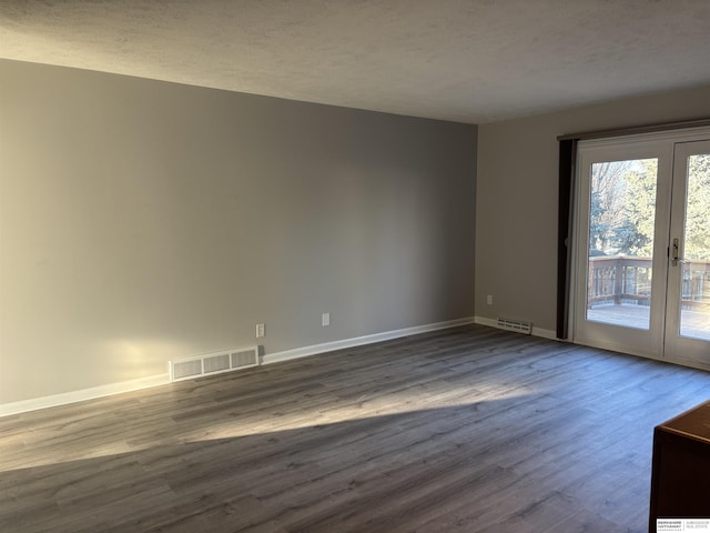 empty room with a healthy amount of sunlight, french doors, a textured ceiling, and hardwood / wood-style flooring