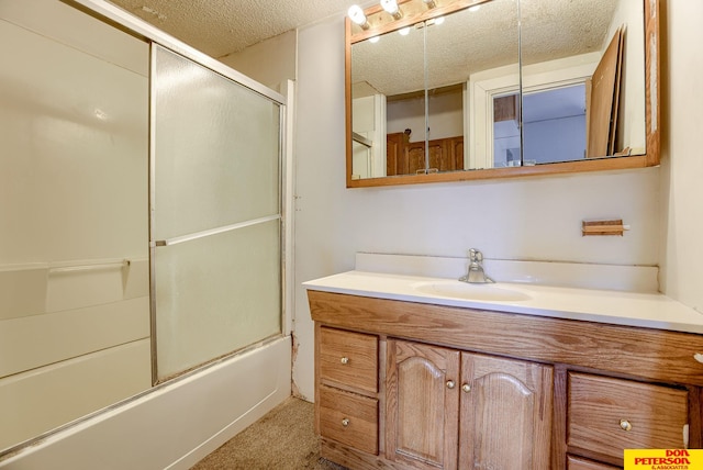 bathroom featuring a textured ceiling, shower / bath combination with glass door, and vanity