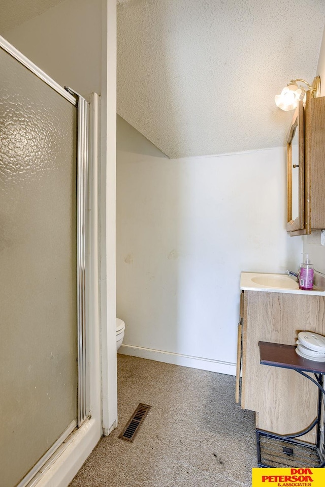 bathroom with a textured ceiling, a shower with door, and vaulted ceiling