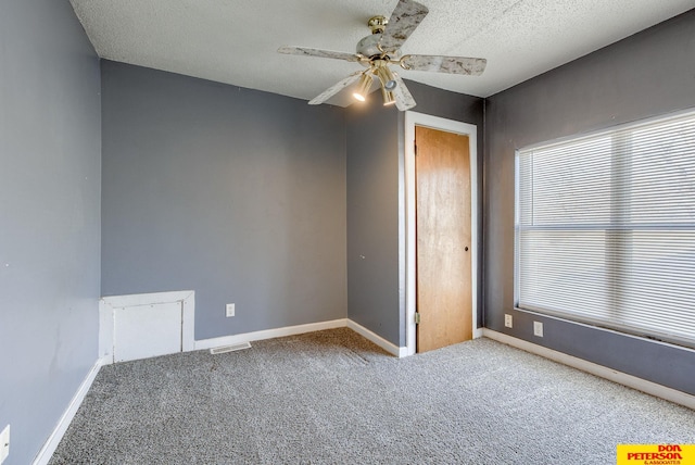 unfurnished bedroom with a textured ceiling, ceiling fan, carpet flooring, and multiple windows