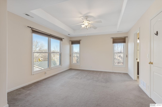 unfurnished room with ceiling fan, light colored carpet, and a raised ceiling