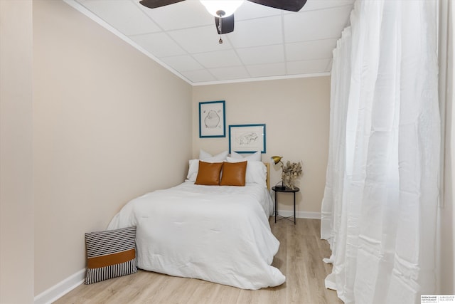 bedroom with ceiling fan, a drop ceiling, and hardwood / wood-style flooring