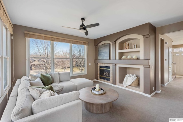 living room featuring a tile fireplace, light colored carpet, and ceiling fan