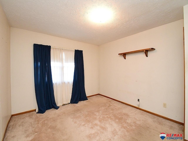 spare room with a textured ceiling and light carpet