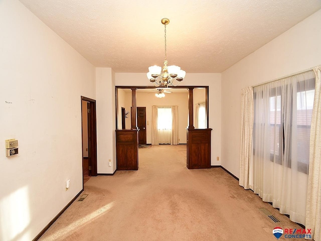 spare room with a notable chandelier, light carpet, and plenty of natural light