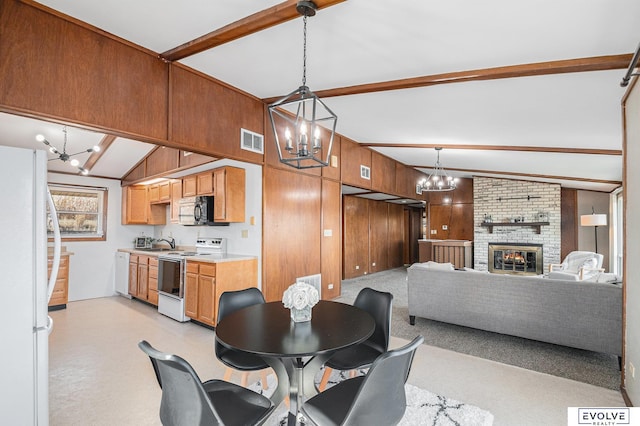 dining space featuring sink, wood walls, lofted ceiling with beams, and a fireplace