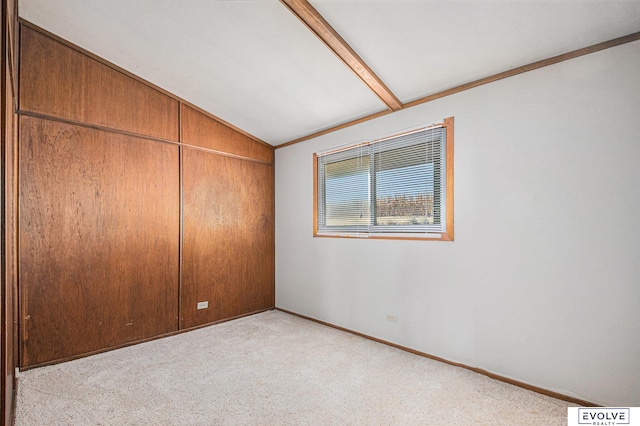 carpeted empty room featuring vaulted ceiling with beams