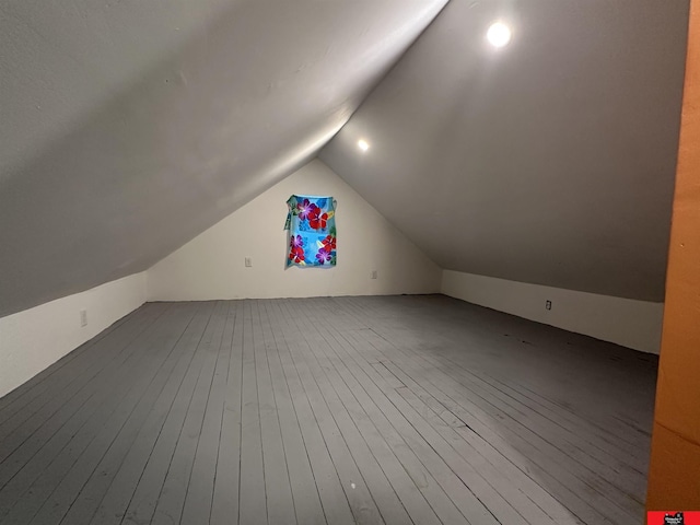 additional living space with hardwood / wood-style flooring and vaulted ceiling