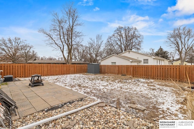 yard covered in snow with a fire pit, central AC unit, and a patio area