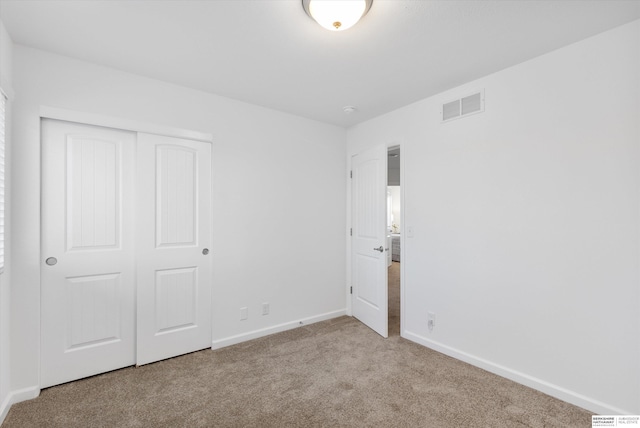 unfurnished bedroom with light carpet and a closet