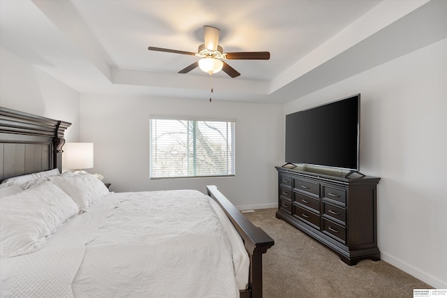 carpeted bedroom with a raised ceiling and ceiling fan