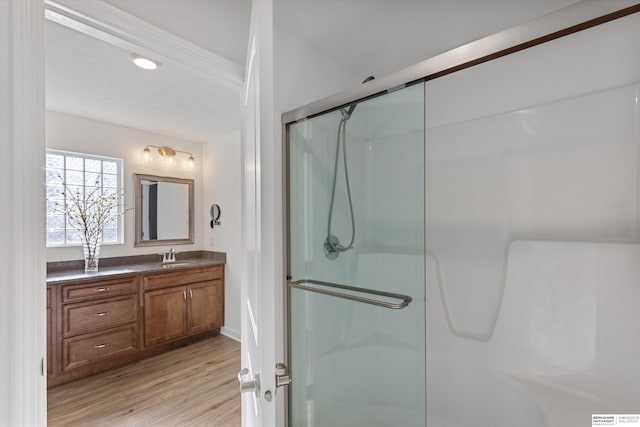 bathroom with wood-type flooring, a shower with door, and vanity