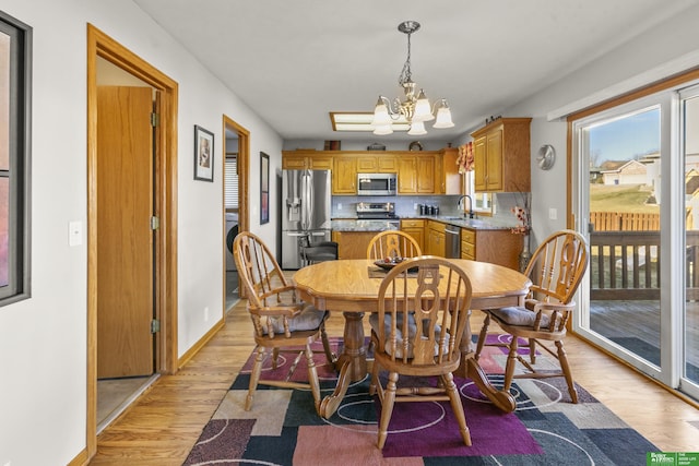 dining space with sink, a chandelier, and light hardwood / wood-style flooring