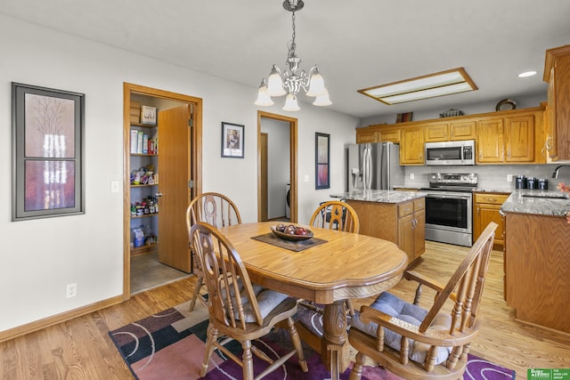 dining area featuring sink, light hardwood / wood-style floors, and a notable chandelier