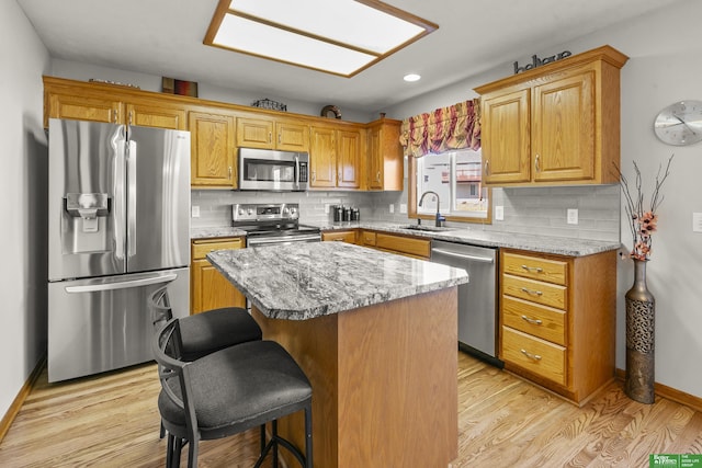 kitchen with a kitchen island, stainless steel appliances, light stone countertops, and sink