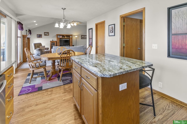 kitchen with a kitchen island, light hardwood / wood-style flooring, decorative light fixtures, and light stone countertops