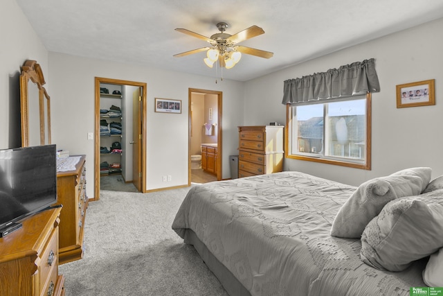 carpeted bedroom with ceiling fan, a spacious closet, ensuite bathroom, and a closet