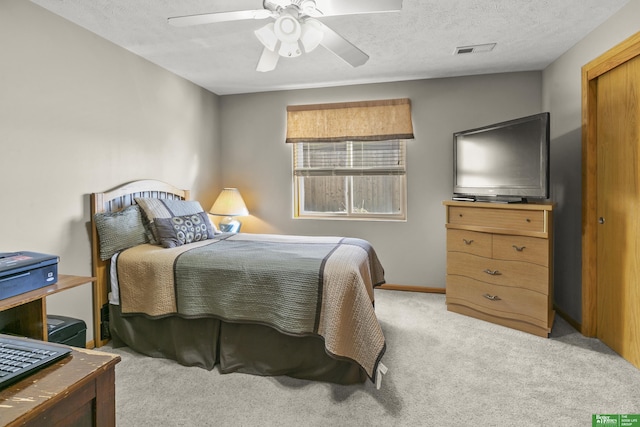 carpeted bedroom featuring ceiling fan and a textured ceiling