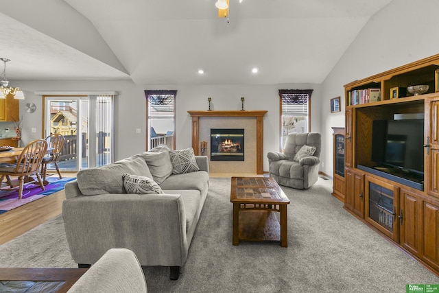 carpeted living room with a tile fireplace, vaulted ceiling, and a healthy amount of sunlight