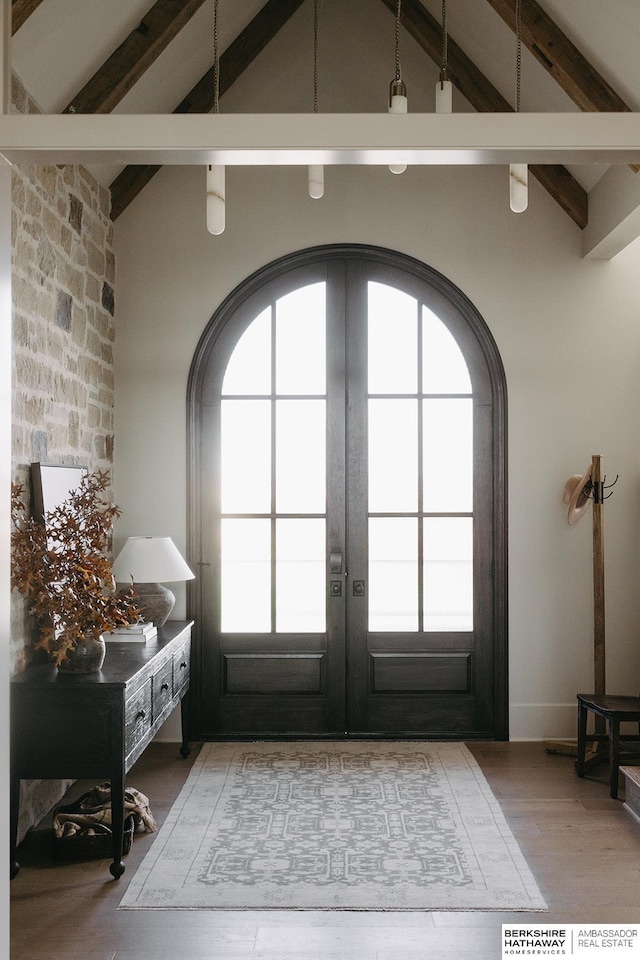 doorway to outside featuring light wood-type flooring, french doors, a wealth of natural light, and vaulted ceiling with beams