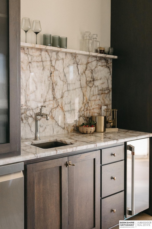 bar featuring sink, decorative backsplash, and light stone counters