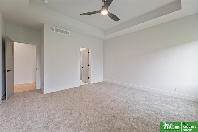 unfurnished bedroom featuring light colored carpet, ceiling fan, and a tray ceiling