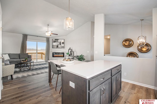 kitchen with a center island, vaulted ceiling, dark brown cabinets, dark hardwood / wood-style flooring, and pendant lighting