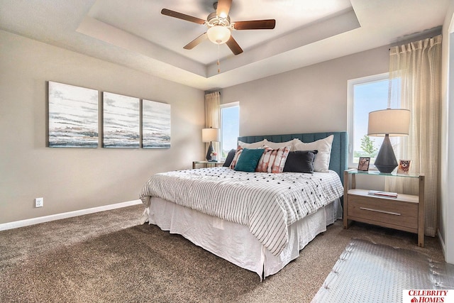 carpeted bedroom featuring ceiling fan and a raised ceiling