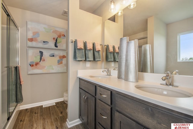 bathroom featuring toilet, vanity, walk in shower, and hardwood / wood-style floors