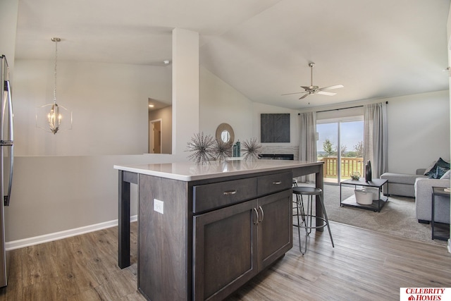 kitchen featuring a kitchen island, vaulted ceiling, a breakfast bar, and hanging light fixtures