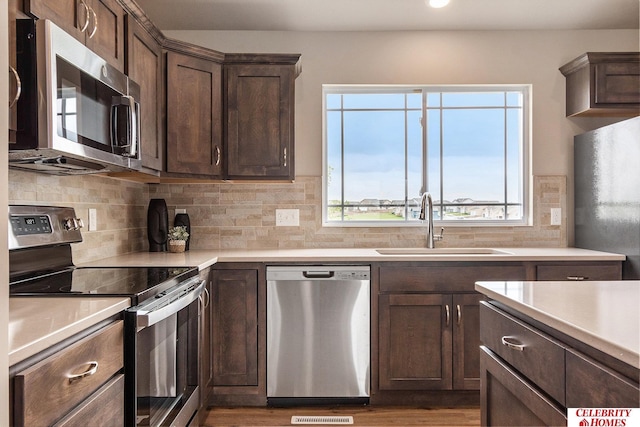 kitchen featuring sink, decorative backsplash, dark brown cabinetry, and appliances with stainless steel finishes