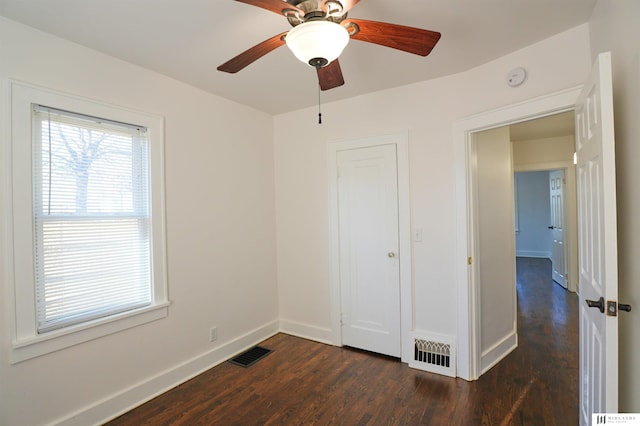 unfurnished bedroom with dark wood-type flooring, ceiling fan, and a closet