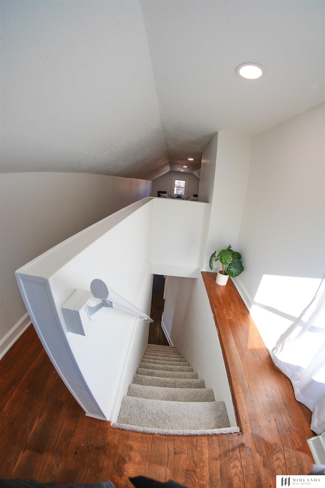 stairway featuring hardwood / wood-style flooring and vaulted ceiling