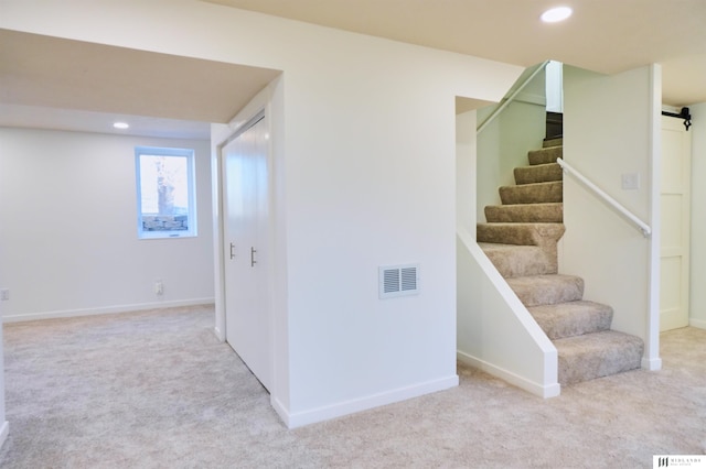 stairs featuring a barn door and carpet