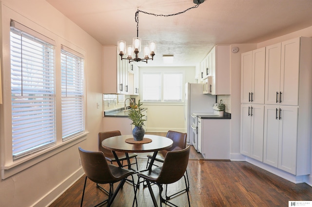 dining room featuring a healthy amount of sunlight, dark hardwood / wood-style flooring, an inviting chandelier, and sink