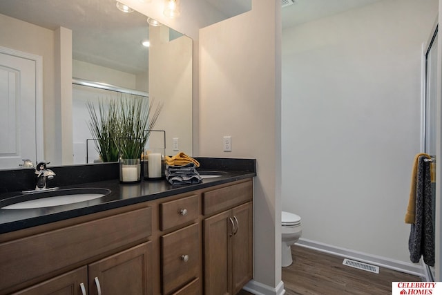 bathroom with toilet, an enclosed shower, wood-type flooring, and vanity